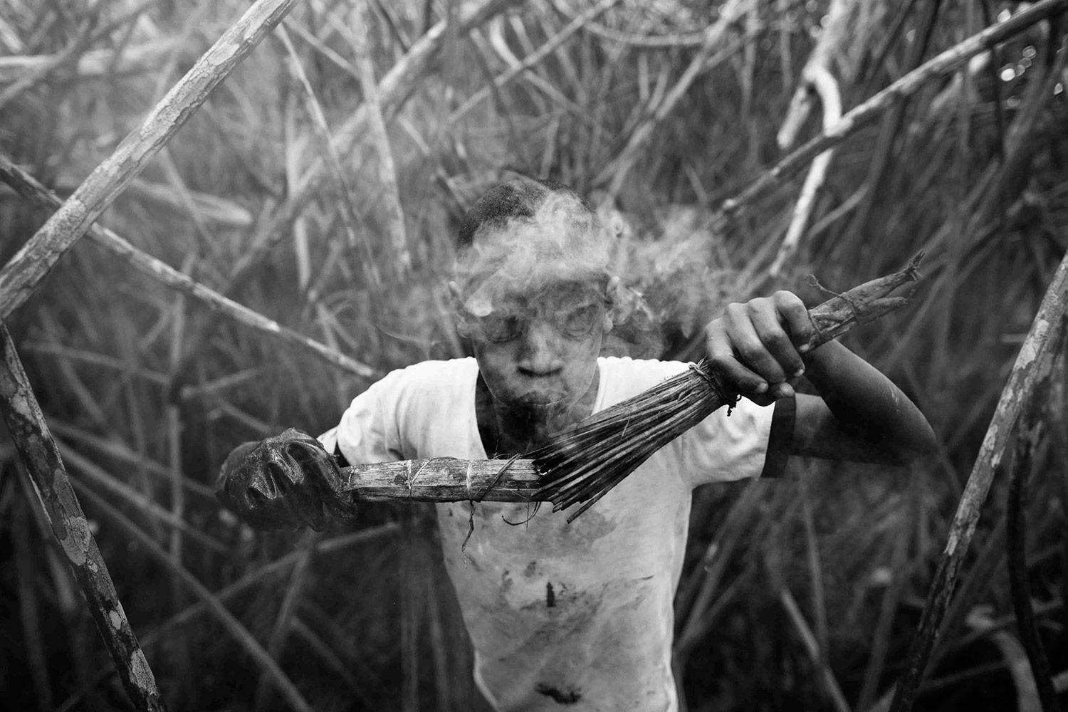 Jeffeson Muñoz ahuyenta a los mosquitos con humo. Foto: Felipe Jácome