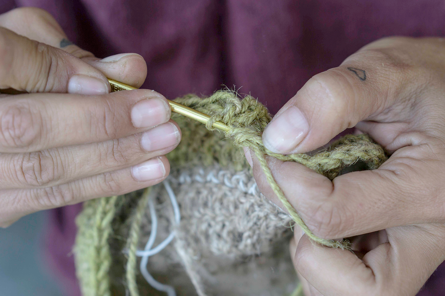Las manos de Francesca tejiendo un sombrero con hilo de cáñamo teñido con curry. Foto: Rocío Periago